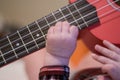 Baby fingers plays guitar. Ukulele strings and frets Royalty Free Stock Photo