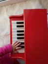 Baby fingers plays music in piano red white colors Royalty Free Stock Photo