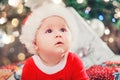 Baby first Christmas. New Year holidays. Baby with santa hat with gift. Living room decorated by Christmas tree and present gift Royalty Free Stock Photo