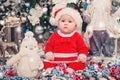 Baby first Christmas. New Year holidays. Baby with santa hat with gift.