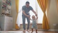 baby first steps. daddy a teaches baby toddler son to take first steps. happy family kid dream concept. baby indoors Royalty Free Stock Photo