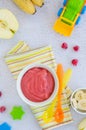 Baby food. Homemade apple puree or sauce with banana and raspberries in a bowl with a spoon on a light background. Healthy food. Royalty Free Stock Photo