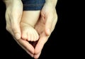 Baby foot in mother hands on black background. Royalty Free Stock Photo