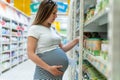 Baby formula pregnant woman shopping. Young pregnant woman buying infant baby formula milk on supermarket background Royalty Free Stock Photo