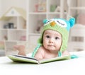 Baby in funny owl knitted hat owl with book in nursery Royalty Free Stock Photo