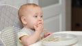 Baby girl with amused expression enjoys eating with hand