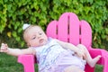 Baby Girl attempting to sit in chair outdoors, leaning over Royalty Free Stock Photo