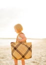 Baby girl with beach bag walking on beach Royalty Free Stock Photo