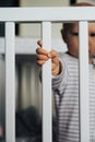 Baby girl with blue eyes and blond standing in her bed, close up on hand Royalty Free Stock Photo