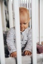 Baby girl with blue eyes and blond standing in her bed, sad and crying Royalty Free Stock Photo