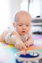 Baby girl with blue eyes playing on mat at floor Royalty Free Stock Photo
