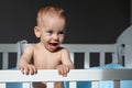 Baby girl with blue eyes standing in crib smiling Royalty Free Stock Photo