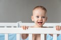 Baby girl with blue eyes standing in crib smiling Royalty Free Stock Photo