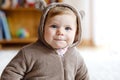 Baby girl with blue eyes wearing brown bear winter overal in sunny bedroom. Newborn child being dressed for an outdoor Royalty Free Stock Photo
