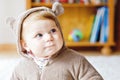 Baby girl with blue eyes wearing brown bear winter overal in sunny bedroom. Newborn child being dressed for an outdoor Royalty Free Stock Photo