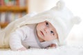 Baby girl with blue eyes wearing white towel or winter overal in white sunny bedroom. Newborn child relaxing in bed Royalty Free Stock Photo