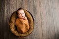 3. Baby girl in a brown wrap is yawning at a newborn photoshoot Royalty Free Stock Photo