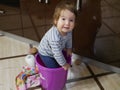 Baby girl in a bucket. Baby boy playing crawled into a bucket. The boy is stuck