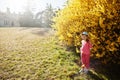 Baby girl in cap at near golden bushes at Lednice park, Czech Republic