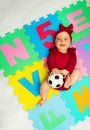 Baby girl on carpet with letters and soccer ball Royalty Free Stock Photo