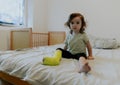 A baby girl with a cast on her leg sits on the bed. Royalty Free Stock Photo