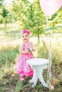 Baby girl celebrating her first bithday with gourmet cake and balloons