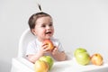 Baby girl in baby chair eating apples on white background. Baby first solid food