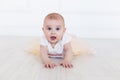 A baby girl is crawling along the floor with an inquisitive and wondering look on her face. Horizontal shot. Cute 6 months girl Royalty Free Stock Photo