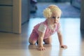 Baby girl crawling along open passage in house