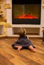 Baby girl crawling near the electric fireplace. Royalty Free Stock Photo