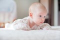 The baby girl crawls on the white bed Royalty Free Stock Photo