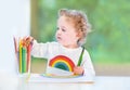 Baby girl with curly hair paiting with colorful pencils Royalty Free Stock Photo