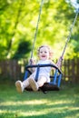 Baby girl with curly hair swinging in sunny park Royalty Free Stock Photo