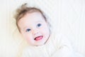 Baby girl with curly hair on a white cable knit blanket Royalty Free Stock Photo