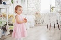 Baby girl in cute dress siting at bed playing with toys by the home. White vintage childroom. Childhood concept