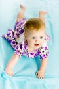 Baby girl in a dress creeps on the blue coverlet Royalty Free Stock Photo