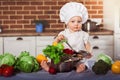 Baby girl dressed in white chef toque and apron