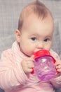 Baby girl drinking water from the red plastic bottle Royalty Free Stock Photo