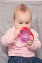 Baby girl drinking water from the red plastic bottle Royalty Free Stock Photo