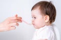 Baby girl eating blend mashed food sitting, on high chair, mother feeding child, hand with spoon for vegetable lunch Royalty Free Stock Photo