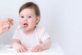 Baby girl eating blend mashed food sitting, on high chair, mother feeding child, hand with spoon for vegetable lunch Royalty Free Stock Photo