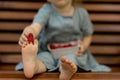 Baby girl eating raspberry on picnic and put on feet.