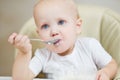 Baby girl eats porridge and looks dreamily in front of herself Royalty Free Stock Photo