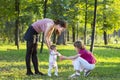 Baby girl first steps with mother and brother in a park