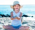 Baby girl in hat playing with sand on sea coast in summer Royalty Free Stock Photo