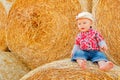 A Baby girl on a haystack happy on the field. Background with children a joyful childhood