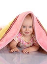 Baby girl is hiding under the blanket over white background Royalty Free Stock Photo