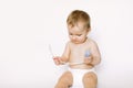 A baby girl holds a nasal aspirator on a white background Royalty Free Stock Photo