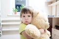 Baby girl hugging teddy bear indoor in her room, devotion concep Royalty Free Stock Photo