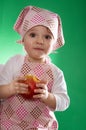 The baby girl with a kerchief and kitchen apron holding an vegetable isolated Royalty Free Stock Photo